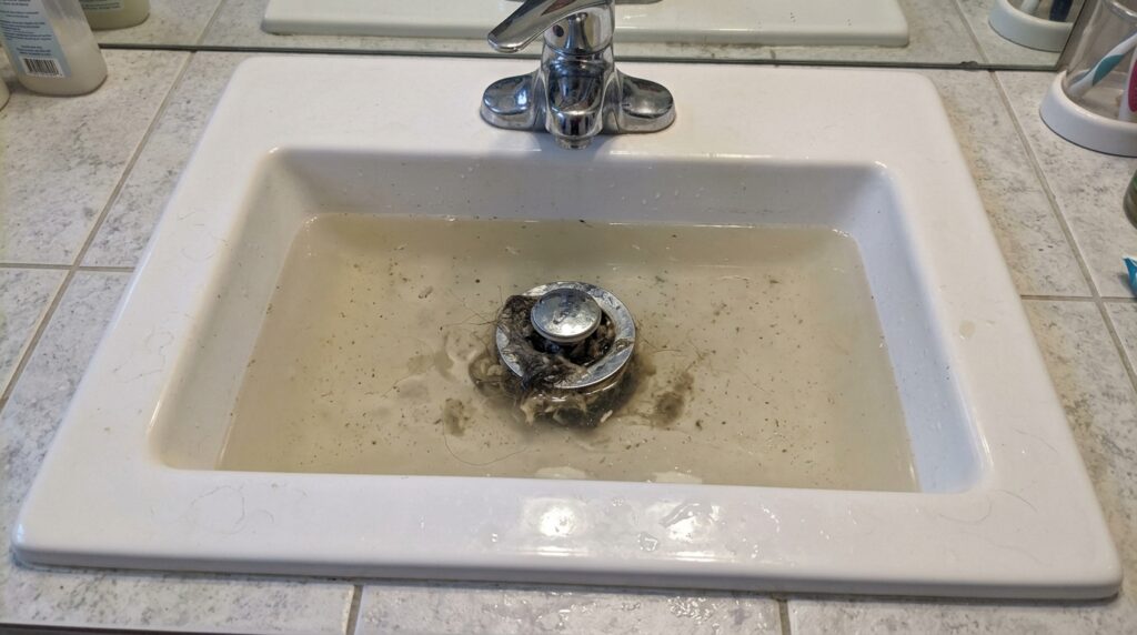 bathroom sink with standing water showing clogged drain that needs to be cleared